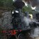 El conductor de un tren sonríe mientras saca la cabeza por la ventana de una maquina a vapor que se desplaza por terrenos montañosos